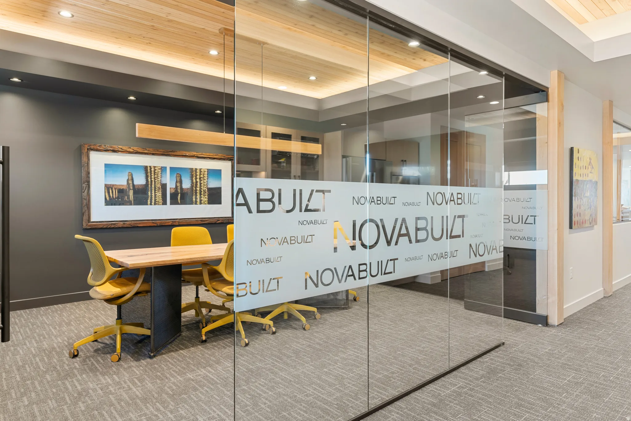 Conference room featuring frosted glass entry, recessed lighting, wood-finish ceiling accents, dark gray wall finishes, and textured carpet flooring