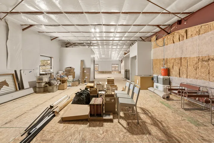 Unfinished interior space featuring exposed wood subflooring, open ceiling with insulation, and rough-in walls