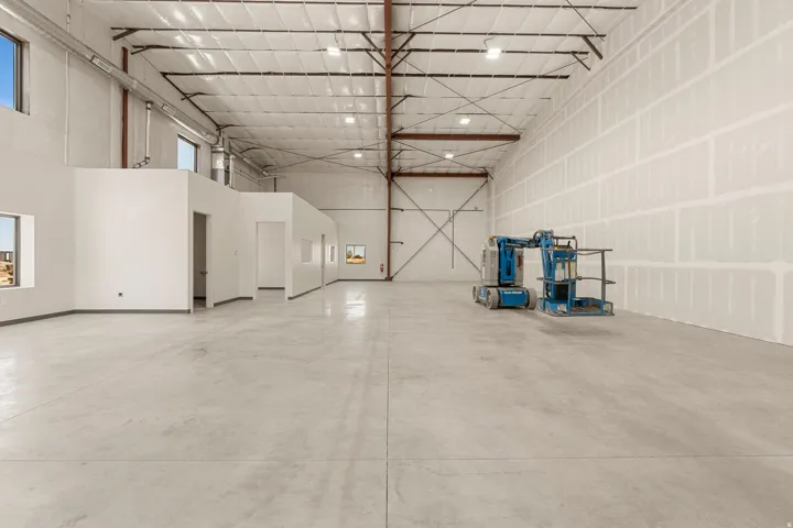 Expansive warehouse interior featuring a polished concrete floor, high ceilings with exposed metal trusses, and multiple windows providing natural light