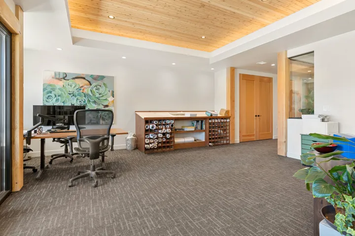 Spacious room featuring a wood-finish coffered ceiling with recessed lighting, light wood doors, and patterned carpet flooring