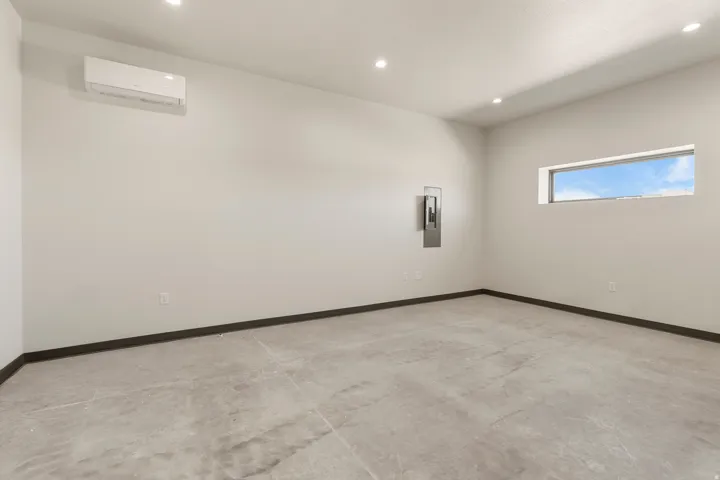 Spacious room featuring light gray walls, dark baseboards, and a polished concrete floor