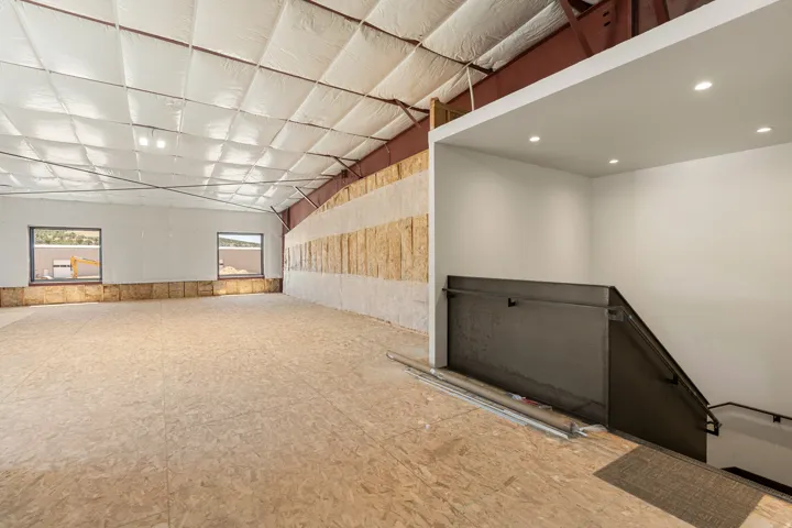 Spacious interior with exposed structural beams, high ceilings, and recessed lighting