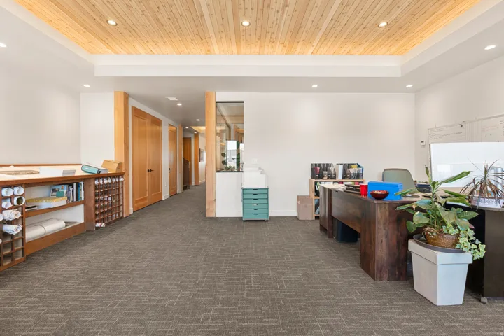 Recessed lighting illuminates a wood-paneled ceiling accent and broadloom carpeting