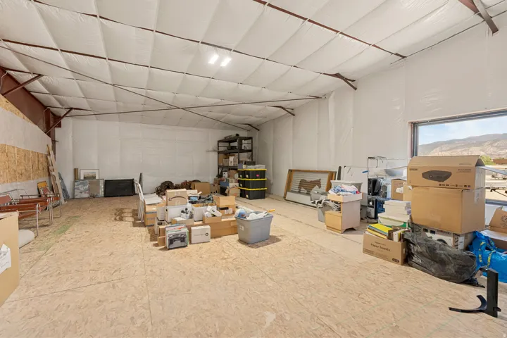 Expansive interior space featuring a high ceiling with exposed structural beams, light-colored insulation, and a large window