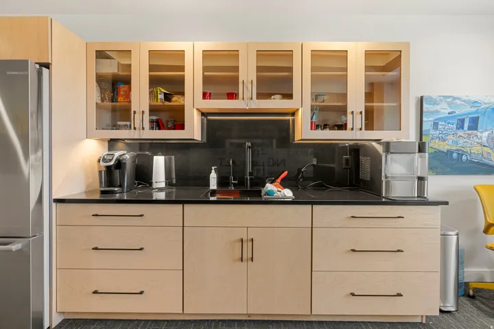 Light wood-finish cabinetry featuring glass-front upper cabinets and black hardware