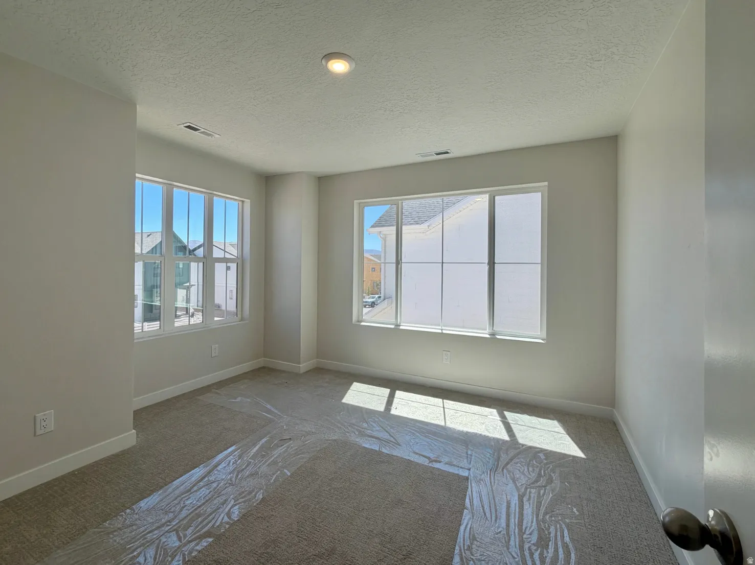 Neutral-toned interior room featuring two large multi-pane windows and recessed lighting