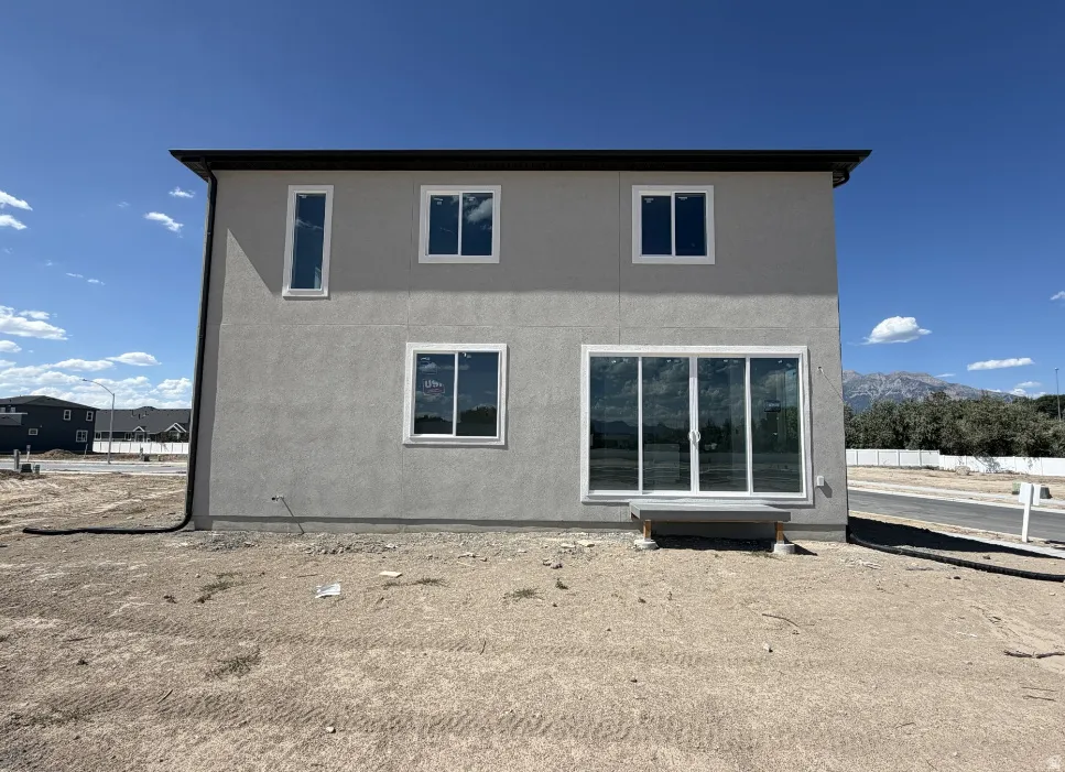 Two-story stucco exterior featuring multiple windows and a prominent sliding glass door
