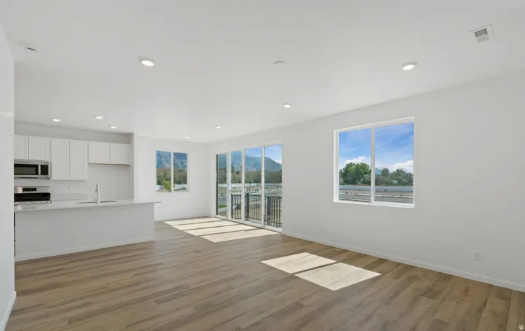 Open-concept living area with wood-finish flooring, recessed lighting, and a sliding glass door to a balcony
