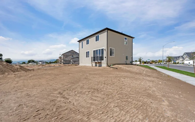 Two-story stucco exterior with multiple windows, a rear deck, and a wide lot