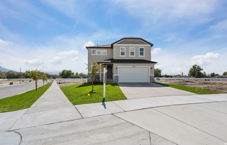 Two-story exterior with stucco and stone accents, a two-car garage, and a concrete driveway