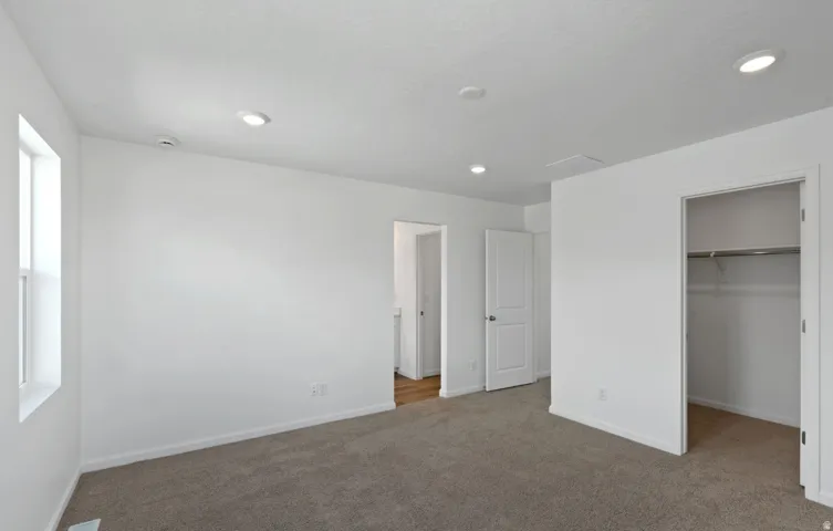 Plush carpeting, recessed lighting, and a window with white trim