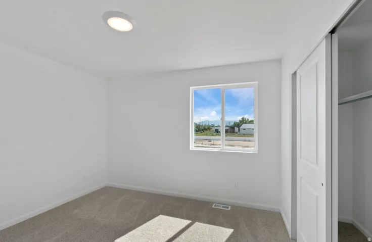 Recessed ceiling lighting, white walls, carpet flooring, a window, and a sliding closet door