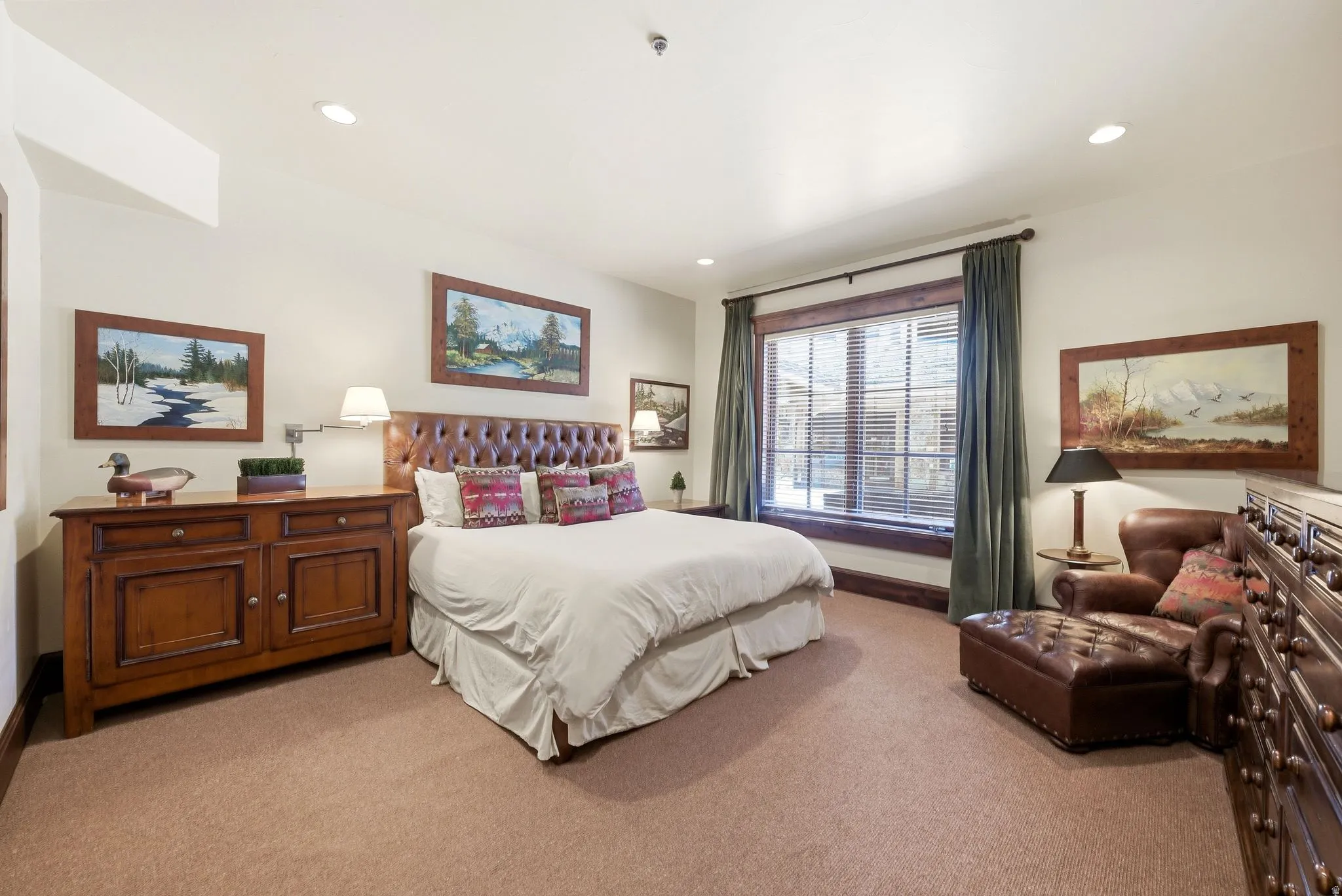 Carpeted room featuring a tufted leather headboard and a window with wood-finish trim
