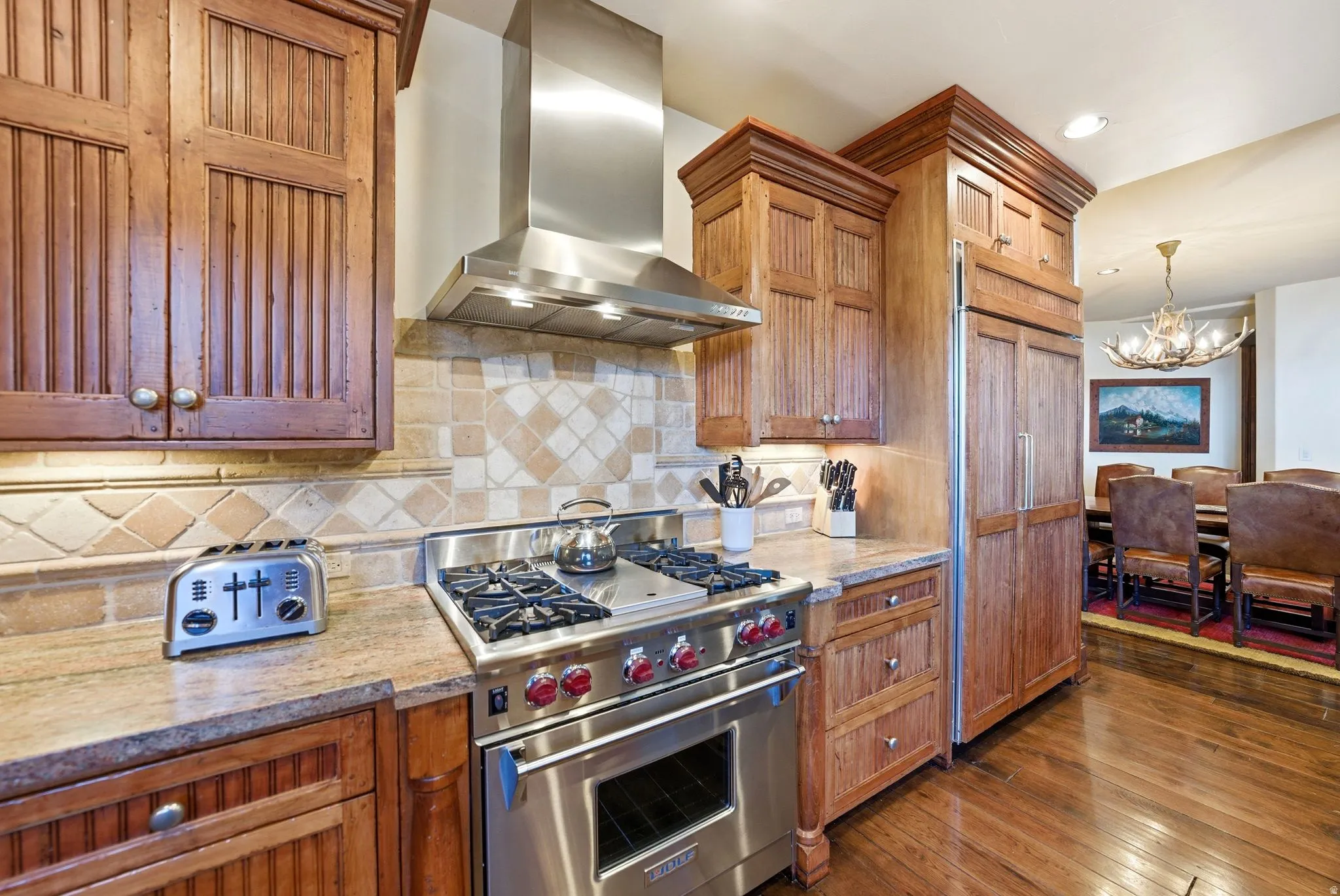 Gourmet kitchen featuring custom wood cabinetry, a stainless steel range with a professional hood, and a paneled refrigerator