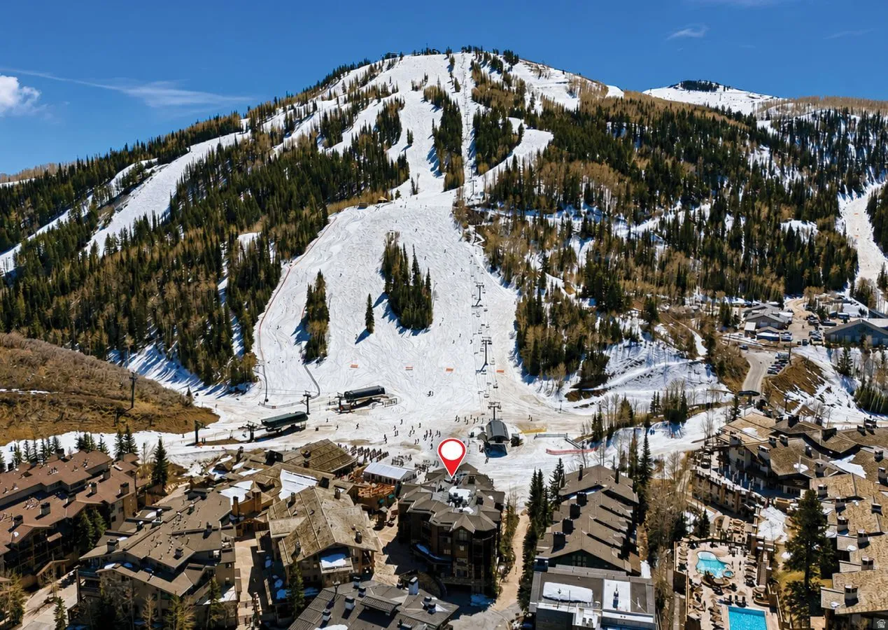 Mountain landscape featuring ski slopes, chairlifts, and surrounding structures with varied rooflines