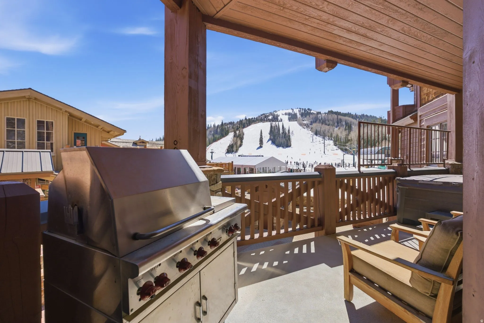 Expansive outdoor patio featuring a stainless steel grill, a built-in hot tub, and a wooden railing
