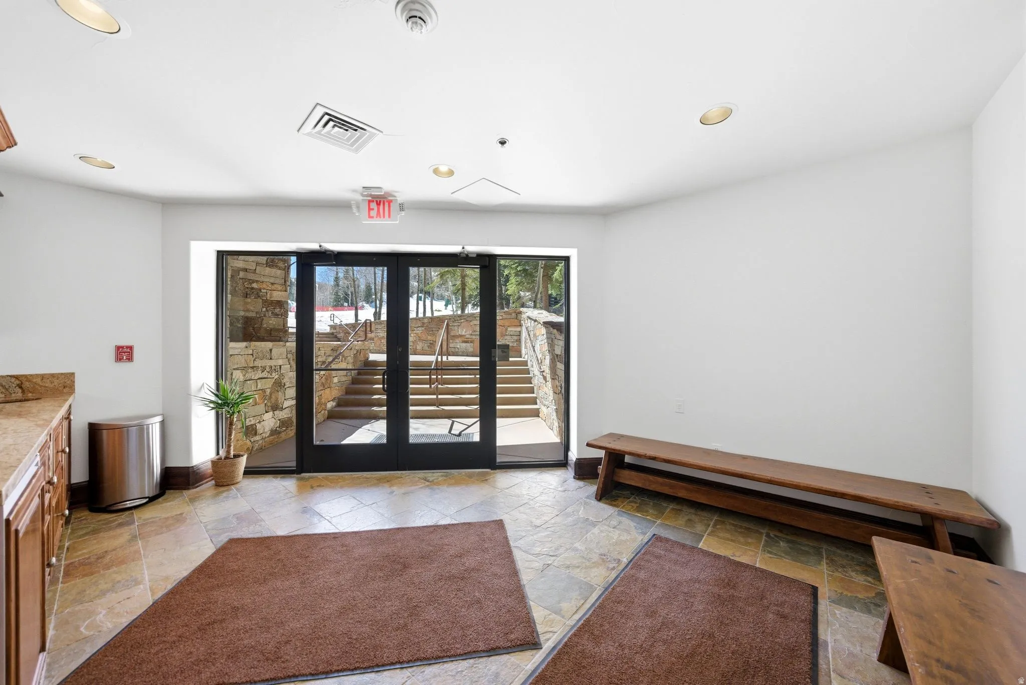 Entryway featuring natural stone tile flooring and glass-paned double doors