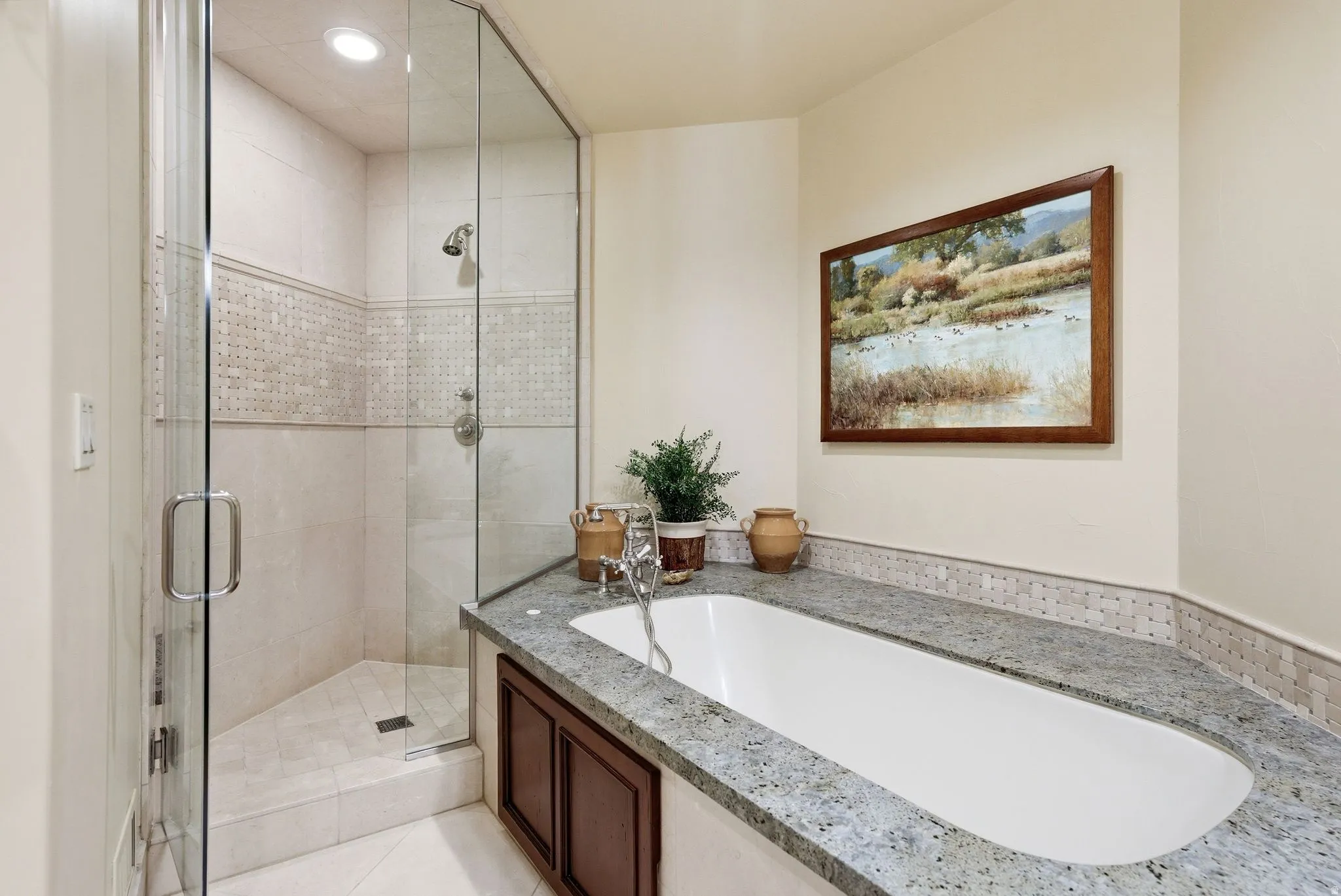 Built-in soaking tub with a speckled countertop and mosaic tile accents