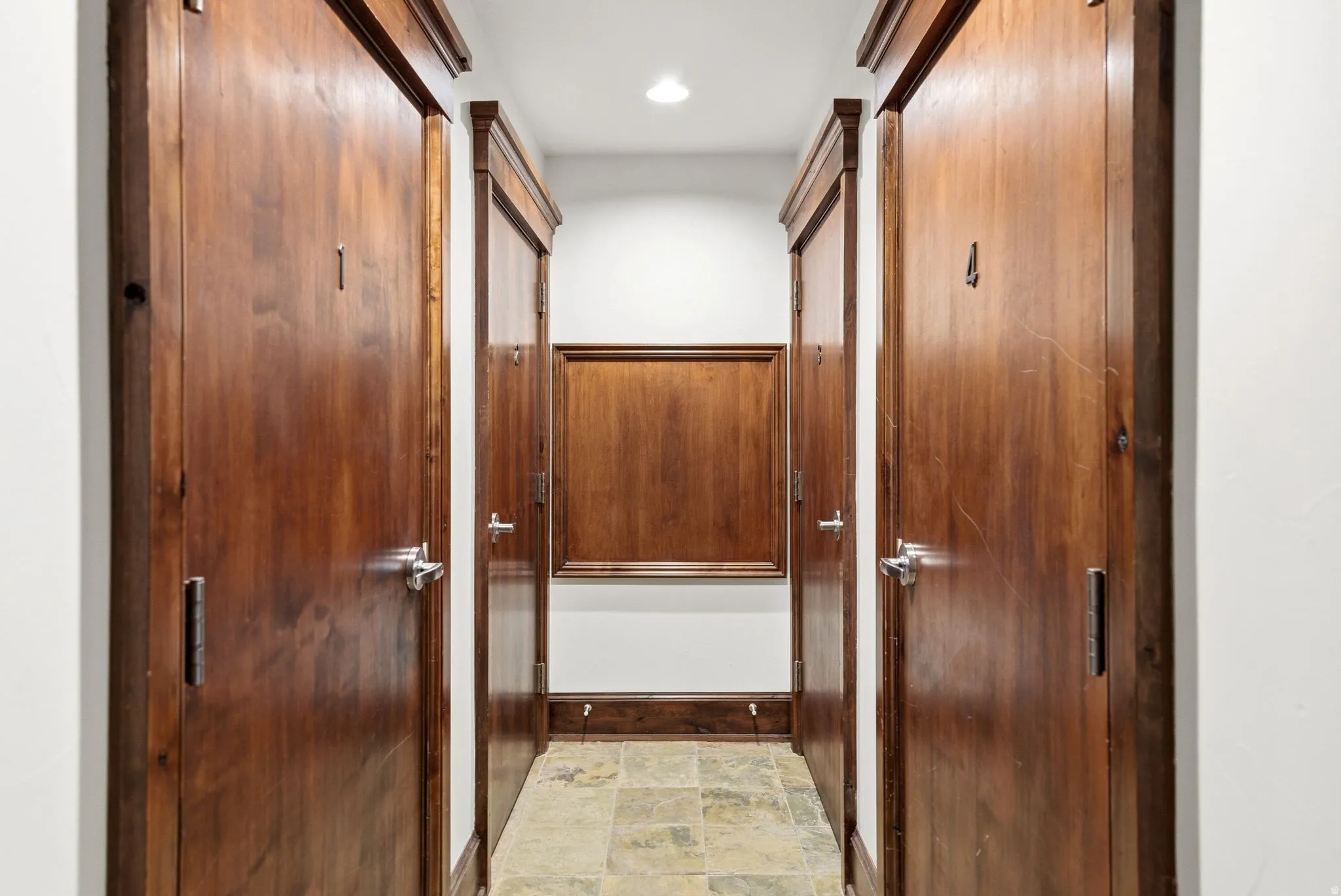 Hallway with five wood-finish doors featuring polished chrome hardware