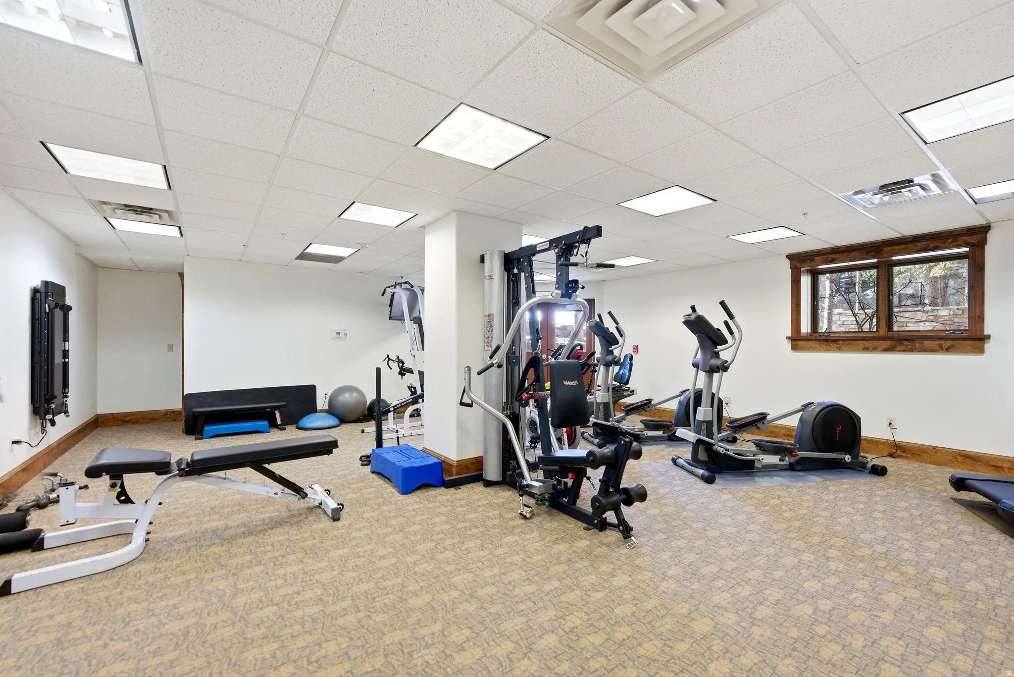 Dedicated fitness area featuring patterned carpet flooring, recessed lighting, and a wood-trimmed window