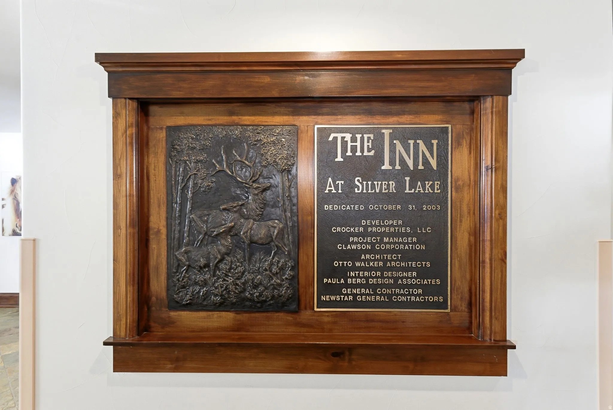 Dark wood-finish framed plaque featuring a bronze-toned relief sculpture and an informational inscription