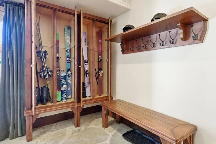 Custom wood-finish storage system featuring recessed compartments with clear panel doors, a built-in wood-finish bench, and a wall-mounted wood-finish shelf with integrated coat hooks