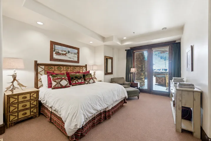 Bedroom featuring a tray ceiling with recessed lighting, wood-finish French doors, and soft carpeting