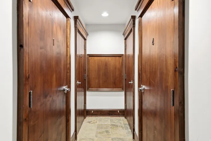 Hallway with five wood-finish doors featuring polished chrome hardware