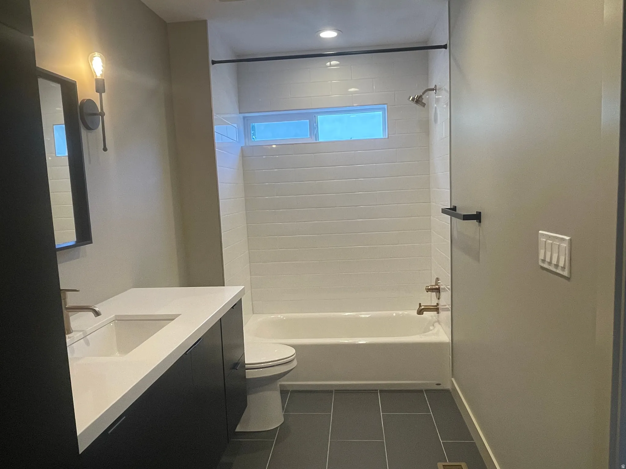 Bathroom featuring a modern vanity with integrated sink, white countertop, and dark cabinetry