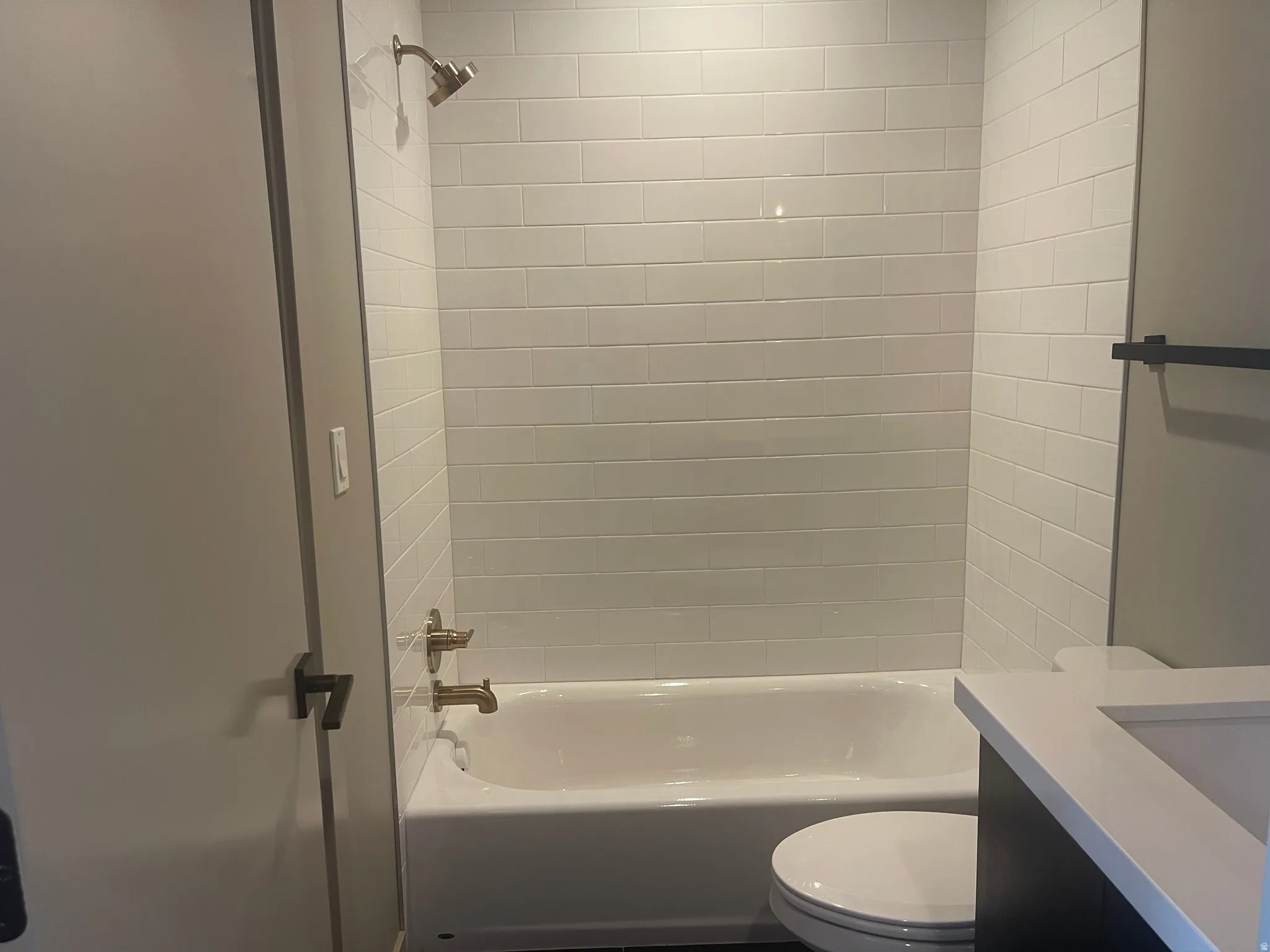 1st floor Bathtub with white subway tile surround, complementing bronze shower and tub fixtures