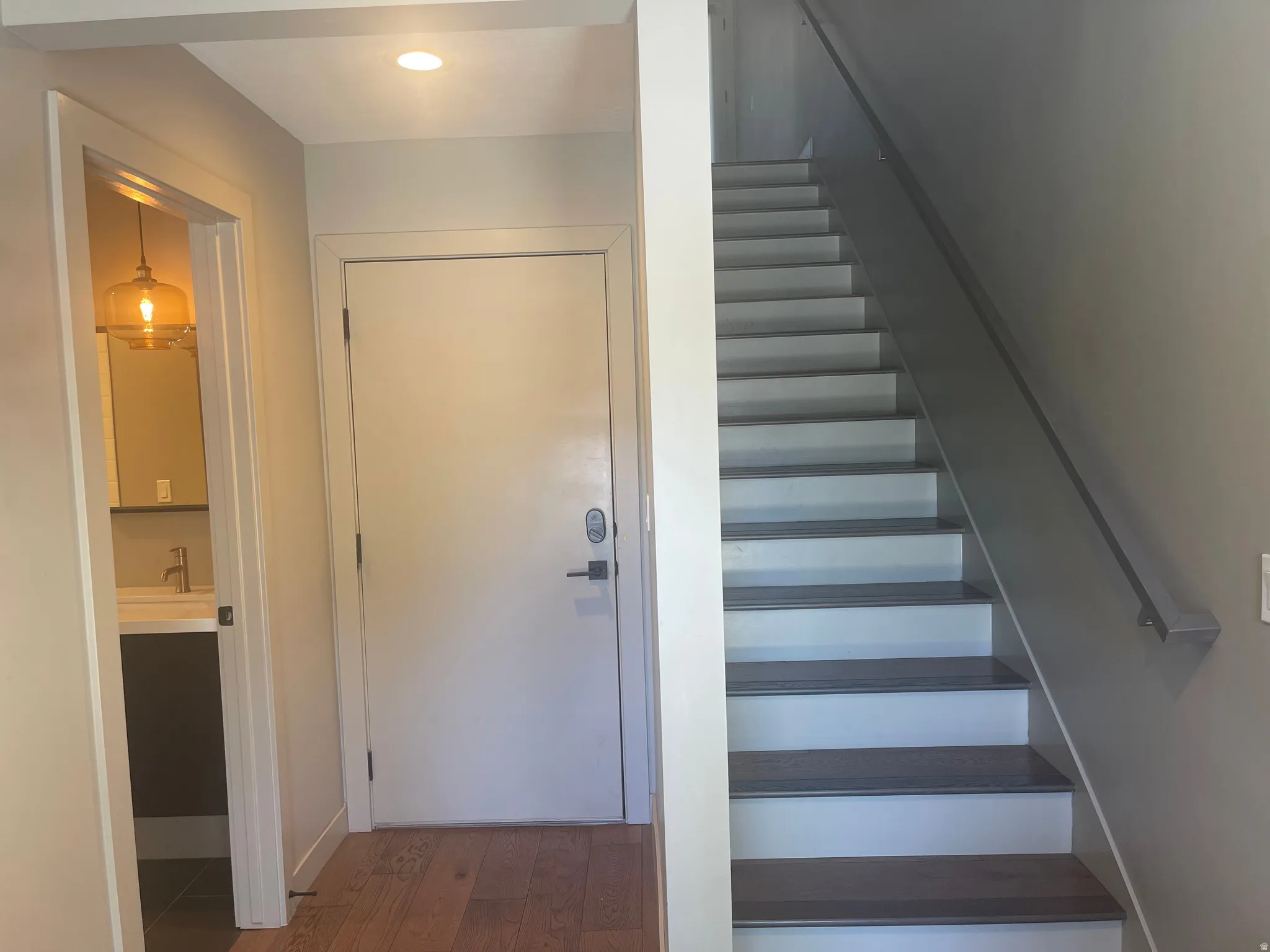 1st Floor Foyer featuring wood-finish flooring, a contemporary staircase with a dark handrail, and a flush-mounted ceiling light