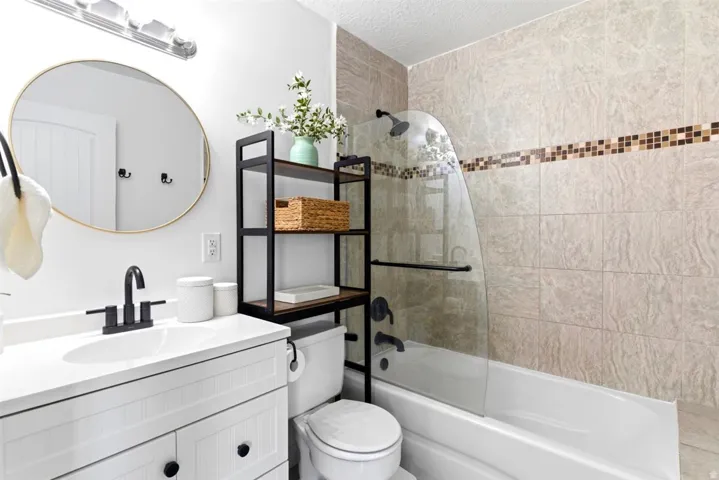 White vanity with black hardware, matte black faucet, and a circular mirror