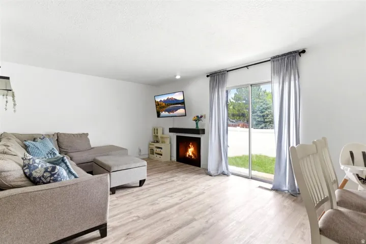 Spacious living area featuring light wood-finish flooring, a contemporary fireplace with a dark mantel, and recessed lighting