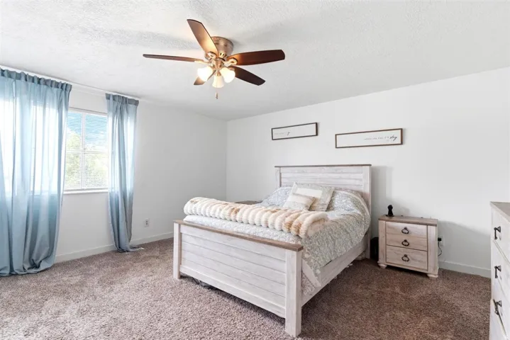 Carpeted room featuring a ceiling fan with integrated lighting, a window with exterior views, and white walls