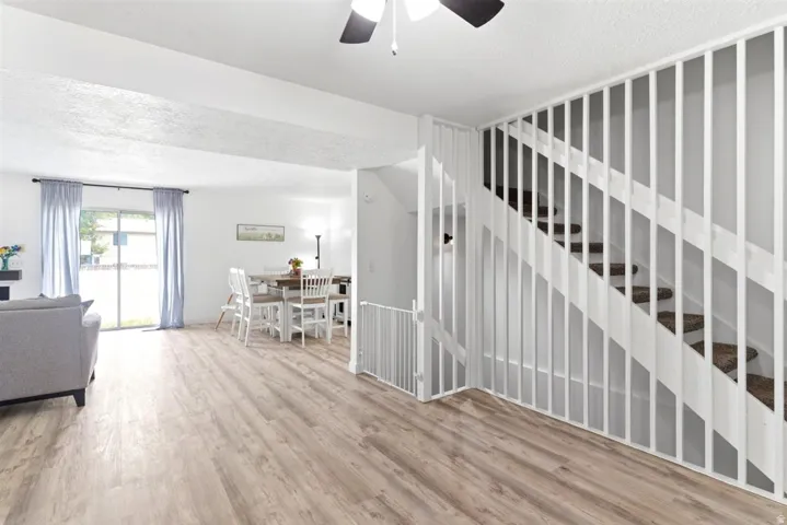 Open-concept living space with wood-finish flooring, white walls, and a ceiling fan