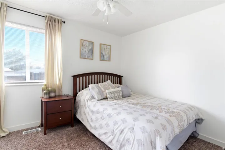 Bedroom featuring a window with horizontal blinds and drapes, white walls, and a ceiling fan