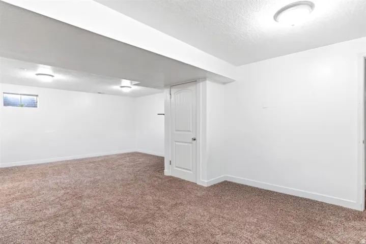 Spacious room featuring neutral carpeting and white painted walls