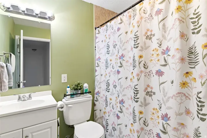 Bathroom featuring a white vanity with integrated sink, chrome faucet, wall-mounted mirror, and overhead light fixture