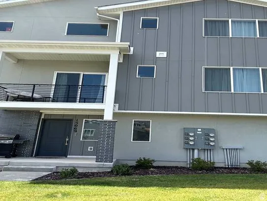 Modern multi-story exterior featuring a balcony with metal railings and a prominent front entry