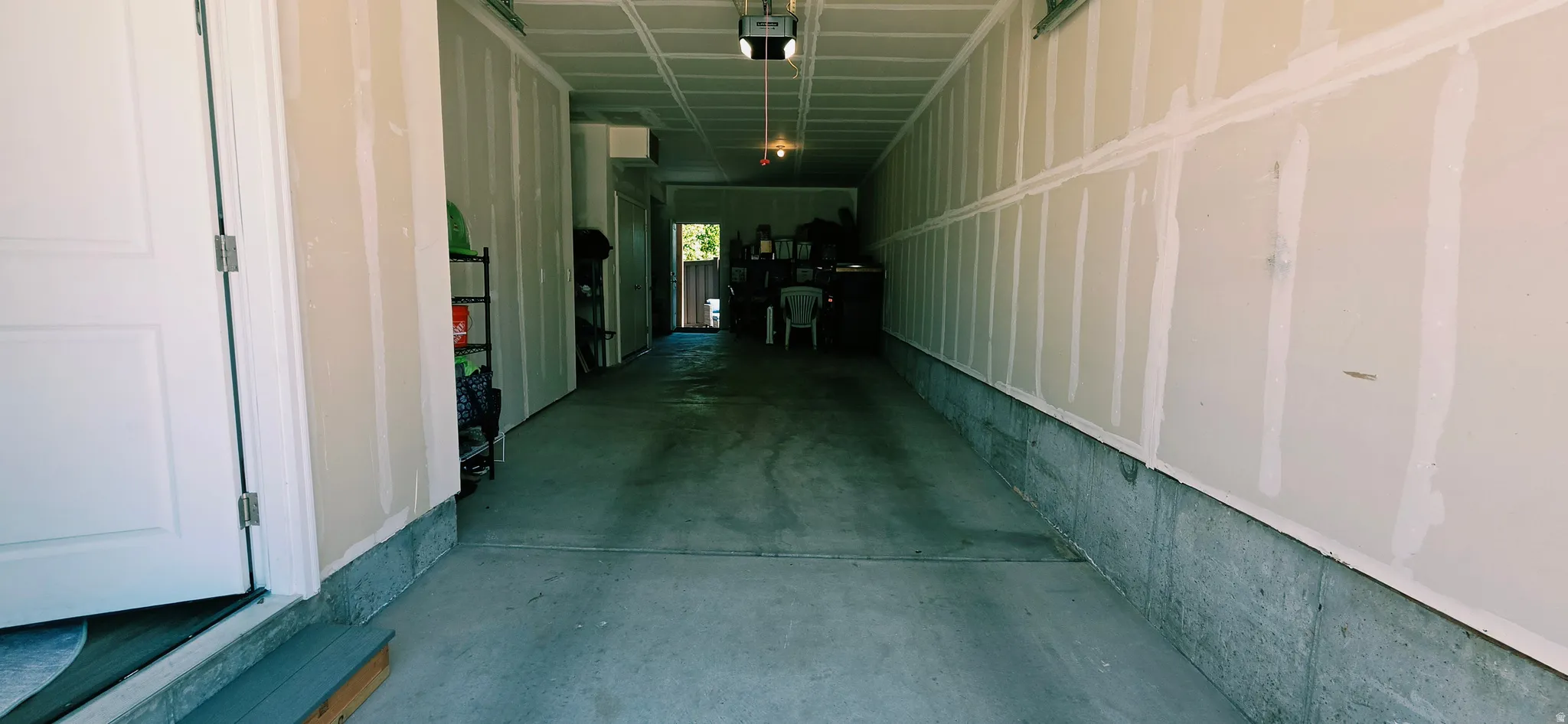 Spacious garage featuring a concrete floor, exposed drywall walls, and overhead lighting