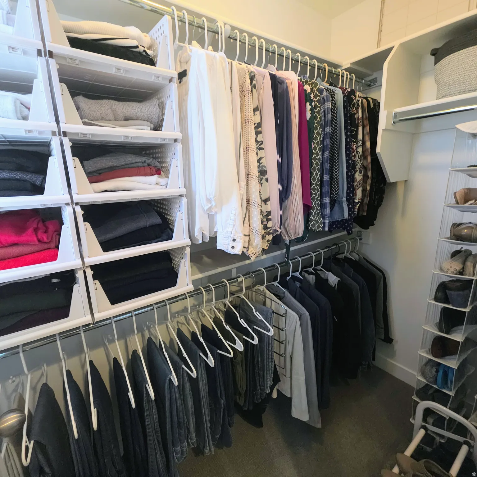 Organized closet system featuring multiple hanging rods, built-in shelving, and white storage baskets