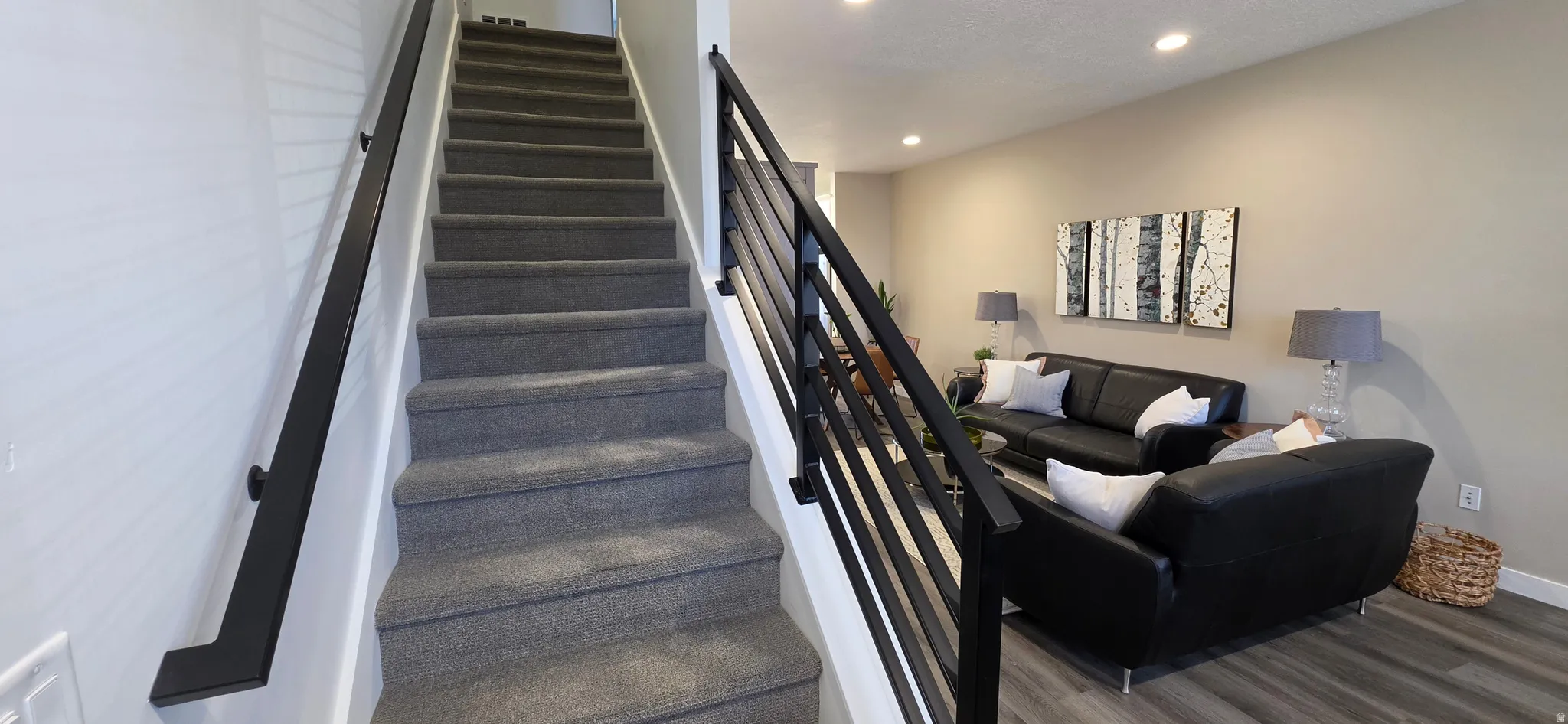 Carpeted staircase featuring a modern black metal railing system