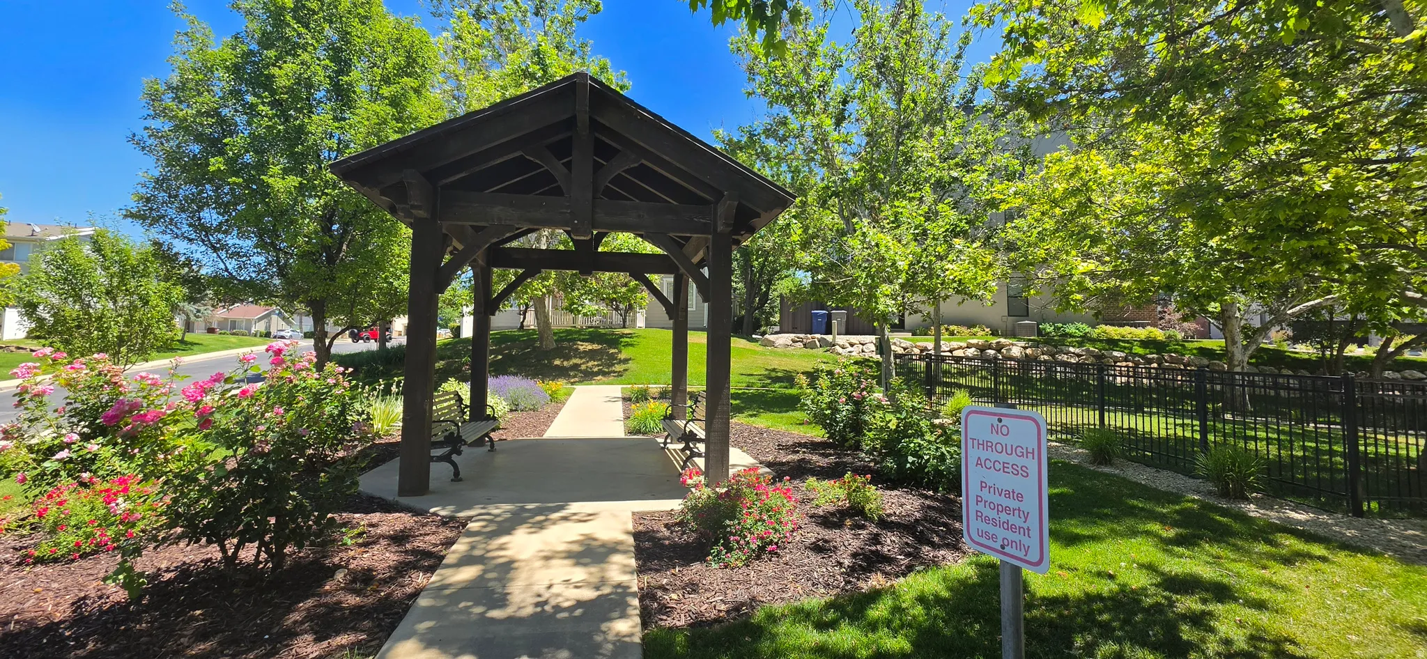 Wood gazebo with built-in benches, set on a concrete pathway