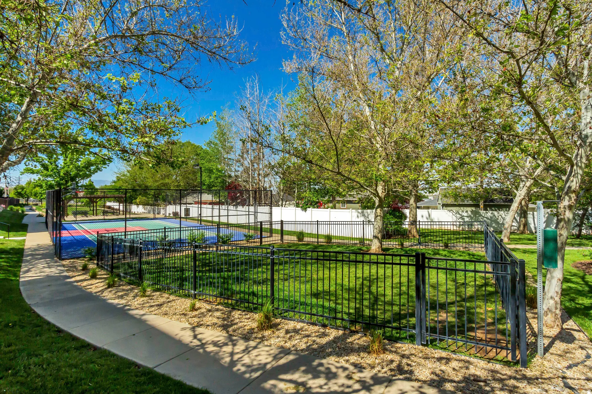 Multi-sport court with vibrant blue, red, and green surfacing, enclosed by black chain-link fencing