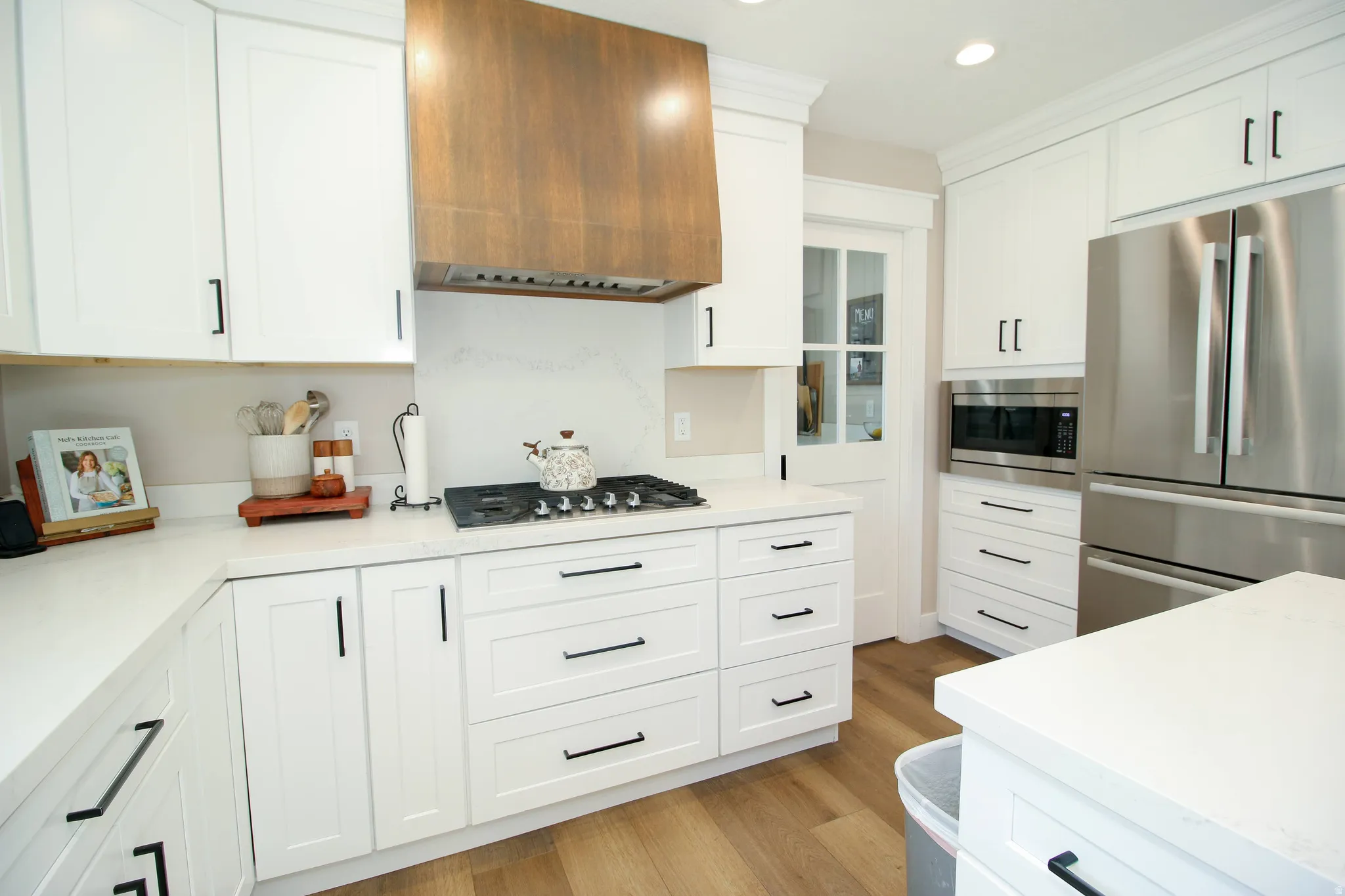 Gourmet kitchen featuring white shaker cabinetry, quartz countertops, and wood-finish flooring