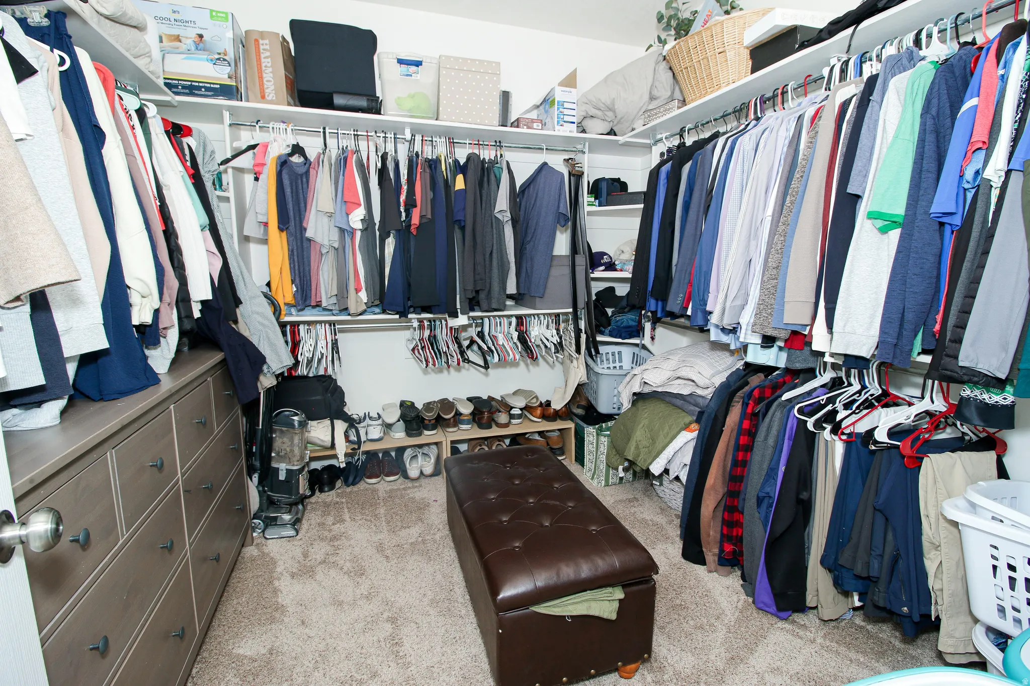 Custom closet system with multiple hanging rods, integrated shelving, and a built-in dresser with dark hardware