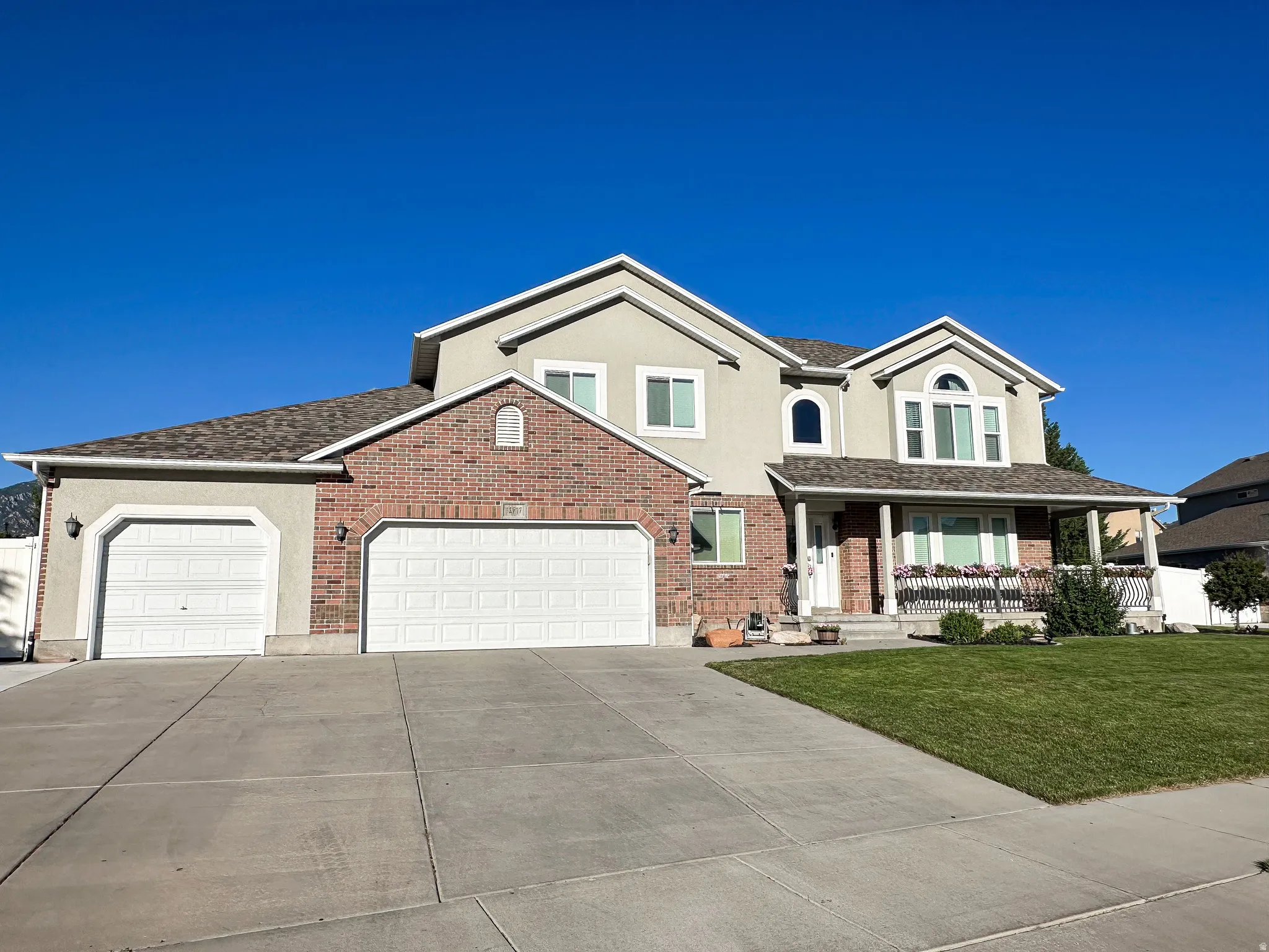 Two-story residence featuring a brick and stucco exterior, a covered front porch, and a concrete driveway