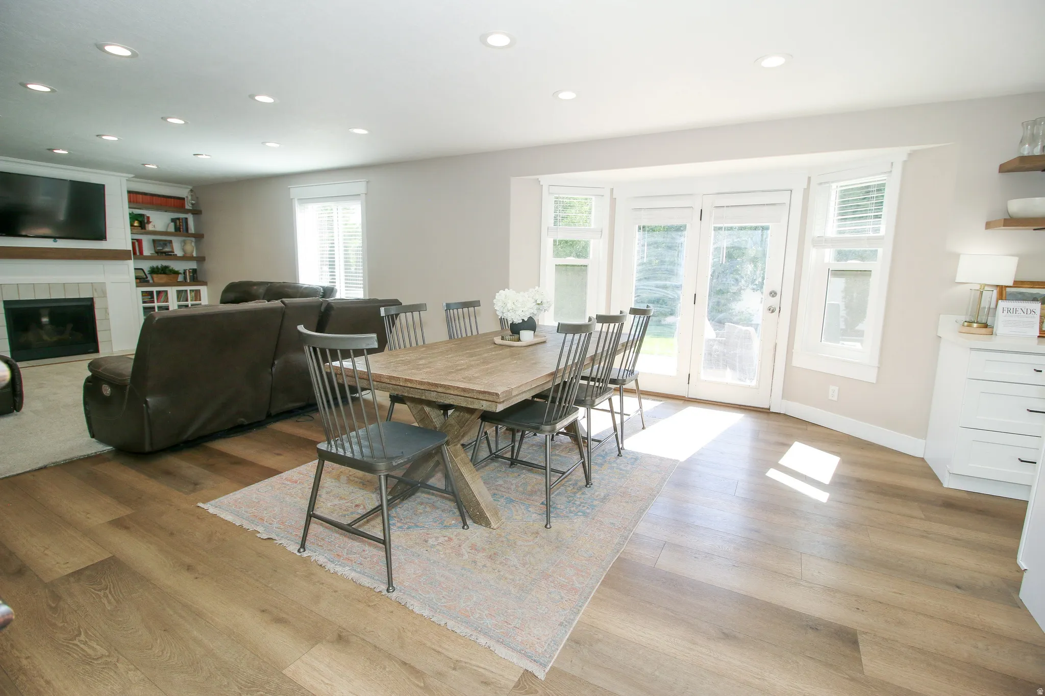 Spacious dining area with wood-finish flooring, recessed lighting, and french doors with flanking windows