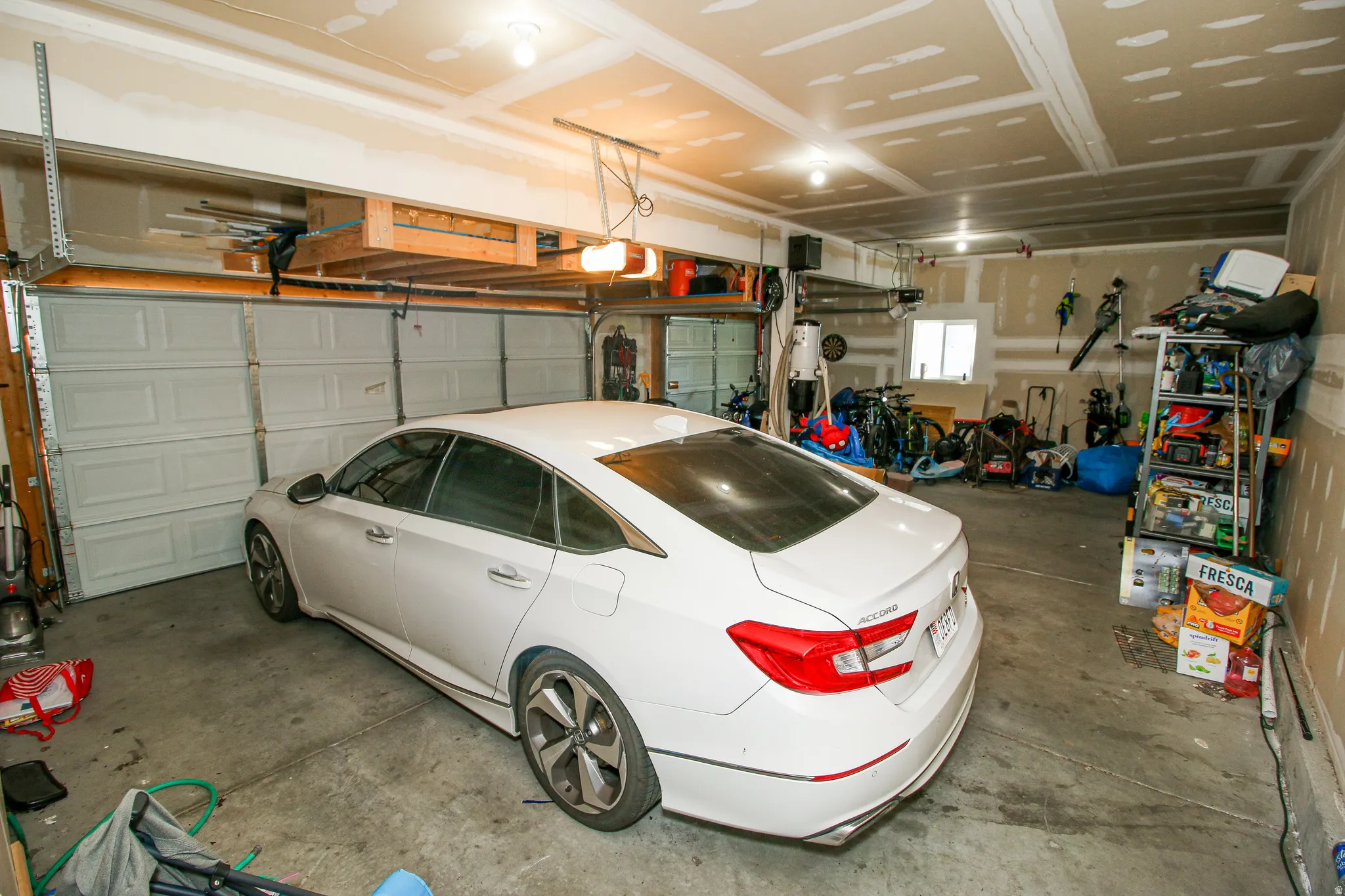 Attached two-car garage featuring a concrete floor, built-in overhead storage, and a single window