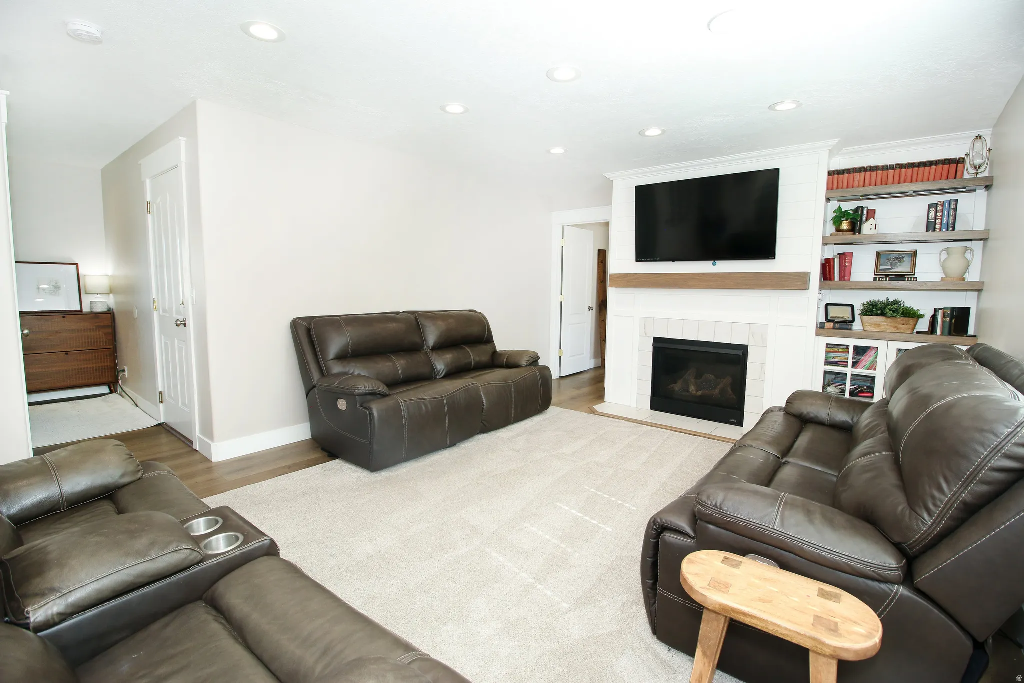 Living area featuring a gas fireplace with a wood mantle, white brick surround, and built-in shelving